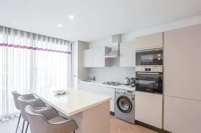 a kitchen with white cabinets and a table and chairs at Résidence Luxuria - Rooftop Pool in Casablanca