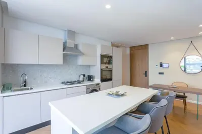 a kitchen with white cabinets and a table and chairs at Résidence Luxuria - Rooftop Pool in Casablanca