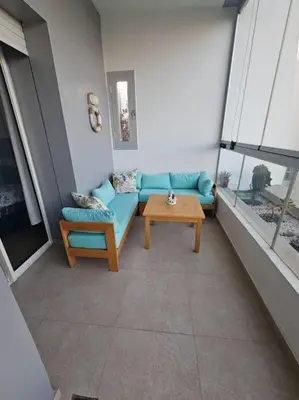 a living room with a blue couch and a table at Sidi Rahal Front mer, piscine & accès direct plage in Dar Oulad Hajj Kassem