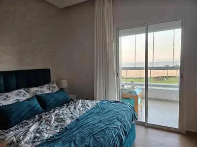 a bedroom with a bed and a view of the ocean at Sidi Rahal Front mer, piscine & accès direct plage in Dar Oulad Hajj Kassem