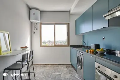 a kitchen with blue cabinets and a window at StayHere Casablanca - Oasis - Premium Residence in Casablanca