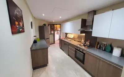a large kitchen with white cabinets and black appliances at Appart chic vue Mer in Casablanca