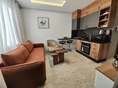 a living room with a couch and a kitchen at Studio Palmiers Maarif in Casablanca