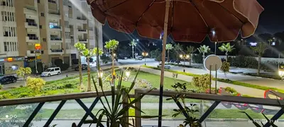 a balcony with an umbrella and a street at night at Suite Meublée à Nouaceur in Nouaceur