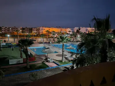 a view of a pool with palm trees and buildings at Appartement au Bord de Mer in Casablanca