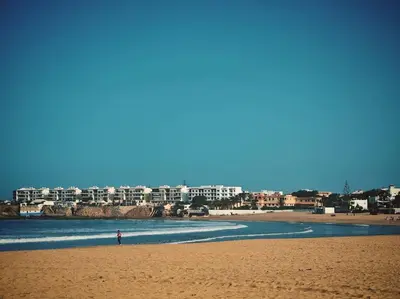 a person standing on a beach with buildings in the background at Appartement au Bord de Mer in Casablanca