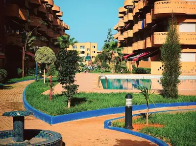 a building with a courtyard with trees and a pool at Appartement au Bord de Mer in Casablanca