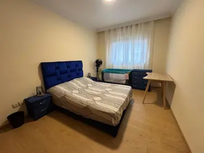 a bedroom with a bed and a table and a window at Appartement moderne avec parking - Proche Mall in Rabat