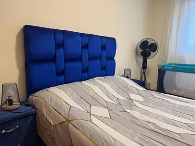 a bed with a blue headboard in a bedroom at Appartement moderne avec parking - Proche Mall in Rabat
