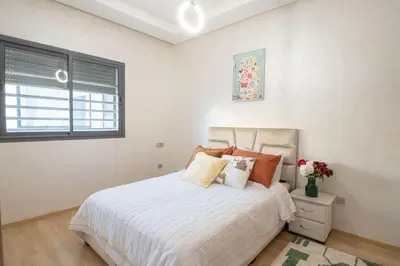 a bedroom with a white bed and a window at Séjour Élégant et Détente au Bord de la Piscine in Aïn Harrouda