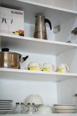 a kitchen shelf with dishes and pots and pans at Cosy appartement 2 BR avec vue panoramique piscine in Aïn Harrouda