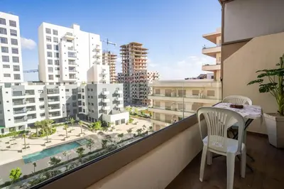 a balcony with a table and chairs and a view of a city at Cosy appartement 2 BR avec vue panoramique piscine in Aïn Harrouda