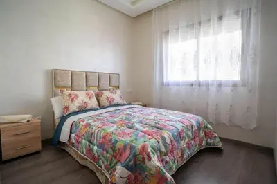 a bedroom with a large bed and a window at Cosy appartement 2 BR avec vue panoramique piscine in Aïn Harrouda