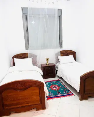 a bedroom with two beds and a rug on the floor at appartement neuf top quartier bouskoura a 2 min de l'Hôpital Universitaire International Mohammed 6 in Casablanca