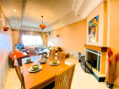 a living room with a table and a fireplace at Cosy calm 2BDR central near train & tramway in Casablanca