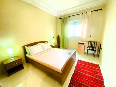 a bedroom with a bed and a table and a chair at Cosy calm 2BDR central near train & tramway in Casablanca
