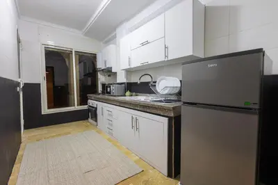 a kitchen with white cabinets and a black refrigerator at Stylish APPT 2 BDR Downtown of Rabat by MERAT HOME in Rabat