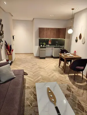 a living room with a table and a kitchen at Studio chaleureux 50m2 avec cuisine au centre de casa et proche du tramway ghandi in Casablanca