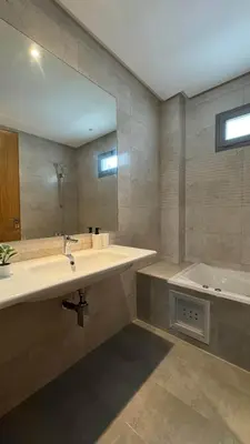 a bathroom with a sink and a tub and a mirror at Maarif 6TH Floor with 3 Bedrooms - AppartAli in Casablanca