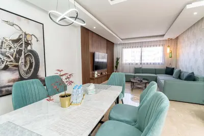 a living room with a table and chairs and a couch at Maarif 6TH Floor with 3 Bedrooms - AppartAli in Casablanca