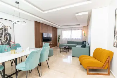 a living room with a table and a yellow couch at Maarif 6TH Floor with 3 Bedrooms - AppartAli in Casablanca