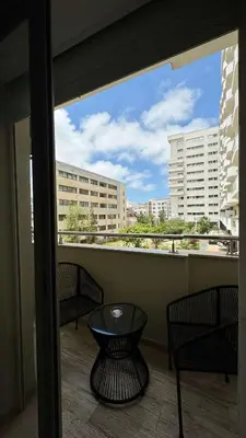 a balcony with three chairs and a table and a window at Maarif 6TH Floor with 3 Bedrooms - AppartAli in Casablanca