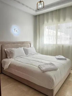 a white bedroom with a large bed with a window at SUITOUISS - Agdal 4 - Appartements à 2 minutes de la gare de train TGV Rabat in Rabat