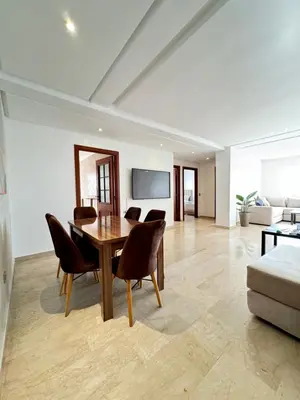 a living room with a table and chairs and a couch at SUITOUISS - Agdal 4 - Appartements à 2 minutes de la gare de train TGV Rabat in Rabat