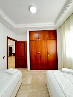a bedroom with two beds and wooden doors at SUITOUISS - Agdal 4 - Appartements à 2 minutes de la gare de train TGV Rabat in Rabat