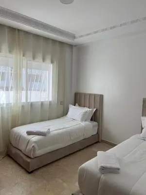 a white bedroom with two beds and a window at SUITOUISS - Agdal 4 - Appartements à 2 minutes de la gare de train TGV Rabat in Rabat