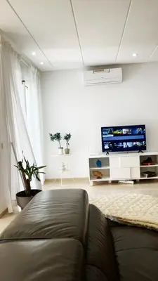 a living room with a couch and a flat screen tv at Seaside studio with pool in Dar Bouazza