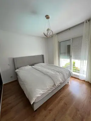 a white bedroom with a bed and a window at villa azur in Dar Bouazza
