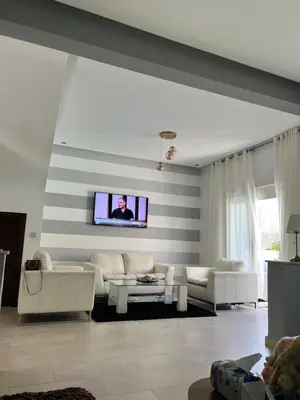 a living room with white furniture and a flat screen tv at villa azur in Dar Bouazza