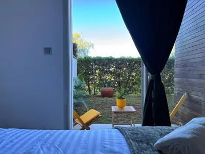 a bedroom with a bed and a window with a chair at Bouskoura, appart jardin privé in Casablanca