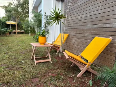 three yellow chairs and a table next to a building at Bouskoura, appart jardin privé in Casablanca