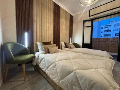 a hotel room with two beds and a chair at Appartement de luxe 155m agdal centre in Rabat