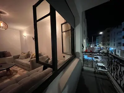 a living room with a couch and a balcony at night at Appartement de luxe 155m agdal centre in Rabat