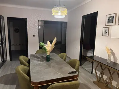 a dining room with a table and green chairs at Appartement de luxe 155m agdal centre in Rabat