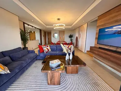 a living room with a blue couch and a tv at Duplex de luxe avec jardin au coeur de la marina in Casablanca