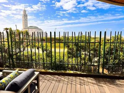 a balcony with a fence and a view of a clock tower at Duplex de luxe avec jardin au coeur de la marina in Casablanca