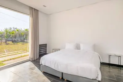 a white bedroom with a large bed and a large window at Villa Luxueuse 4 Chambres au Cœur du Domaine a El Menzeh in El Menzeh