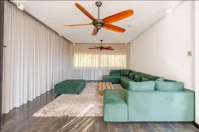 a living room with a green couch and a ceiling fan at Villa Luxueuse 4 Chambres au Cœur du Domaine a El Menzeh in El Menzeh