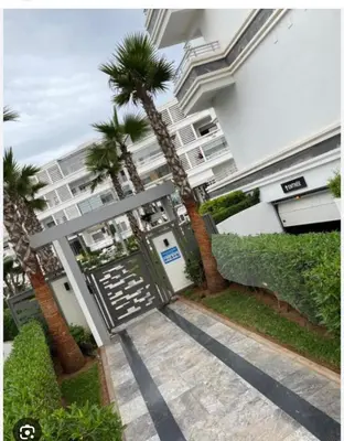 a palm tree in front of a building at Résidences Mansbay Jasmin in Mansouria