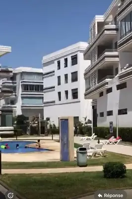 a building with a swimming pool in front of a building at Résidences Mansbay Jasmin in Mansouria