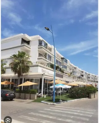 a large white building with umbrellas and a street light at Résidences Mansbay Jasmin in Mansouria