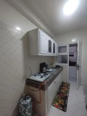 a small kitchen with a stove and white cabinets at Appartement au centre de Rabat Agdal in Rabat