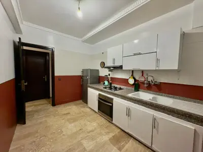 a kitchen with white cabinets and red and white walls at Appartement exceptionnel en plein centre de rabat pour les familles et couples mariés in Rabat