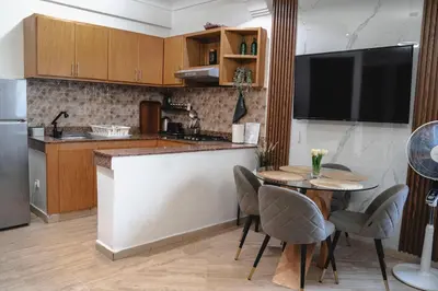a kitchen with a table with chairs and a television at AnfaSuites - Le Central - Parking Free - CasaPort 5min in Casablanca
