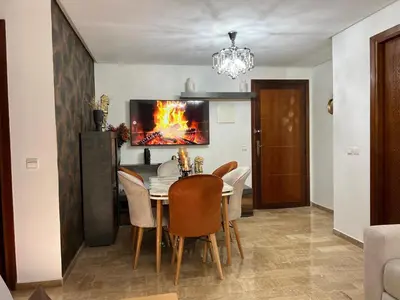 a dining room with a table and chairs and a tv at Charmant Appart Moderne au Cœur de Rabat avec Fibre in Rabat
