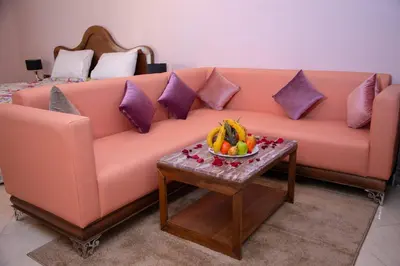 a pink couch with a bowl of fruit on a table at Appart-Hôtel BEL ANFA in Casablanca